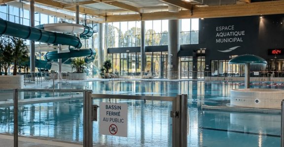Bassin collectif vide, fermé au public, sous un ciel clair